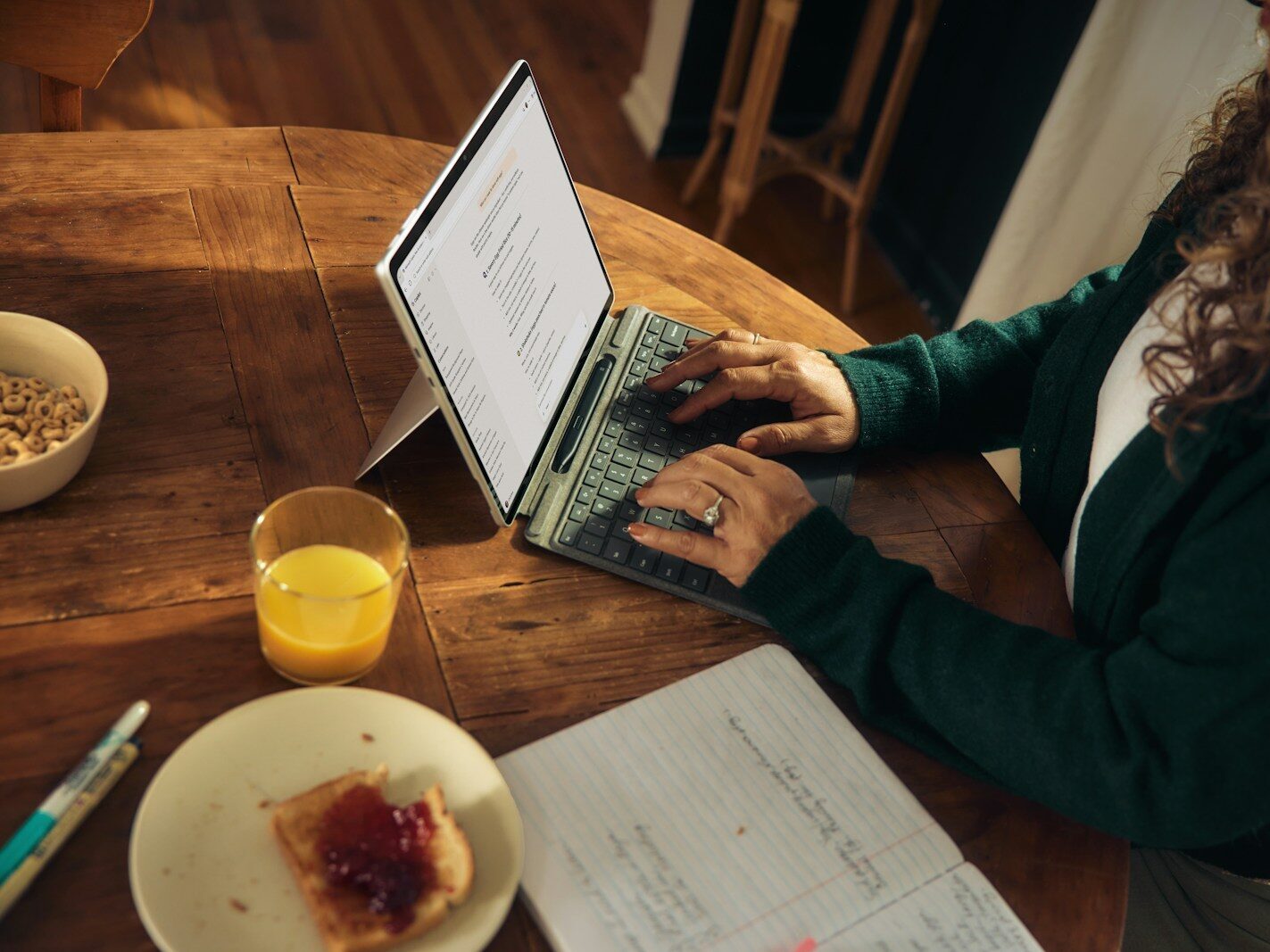 Woman typing on laptop at wooden table with breakfast.